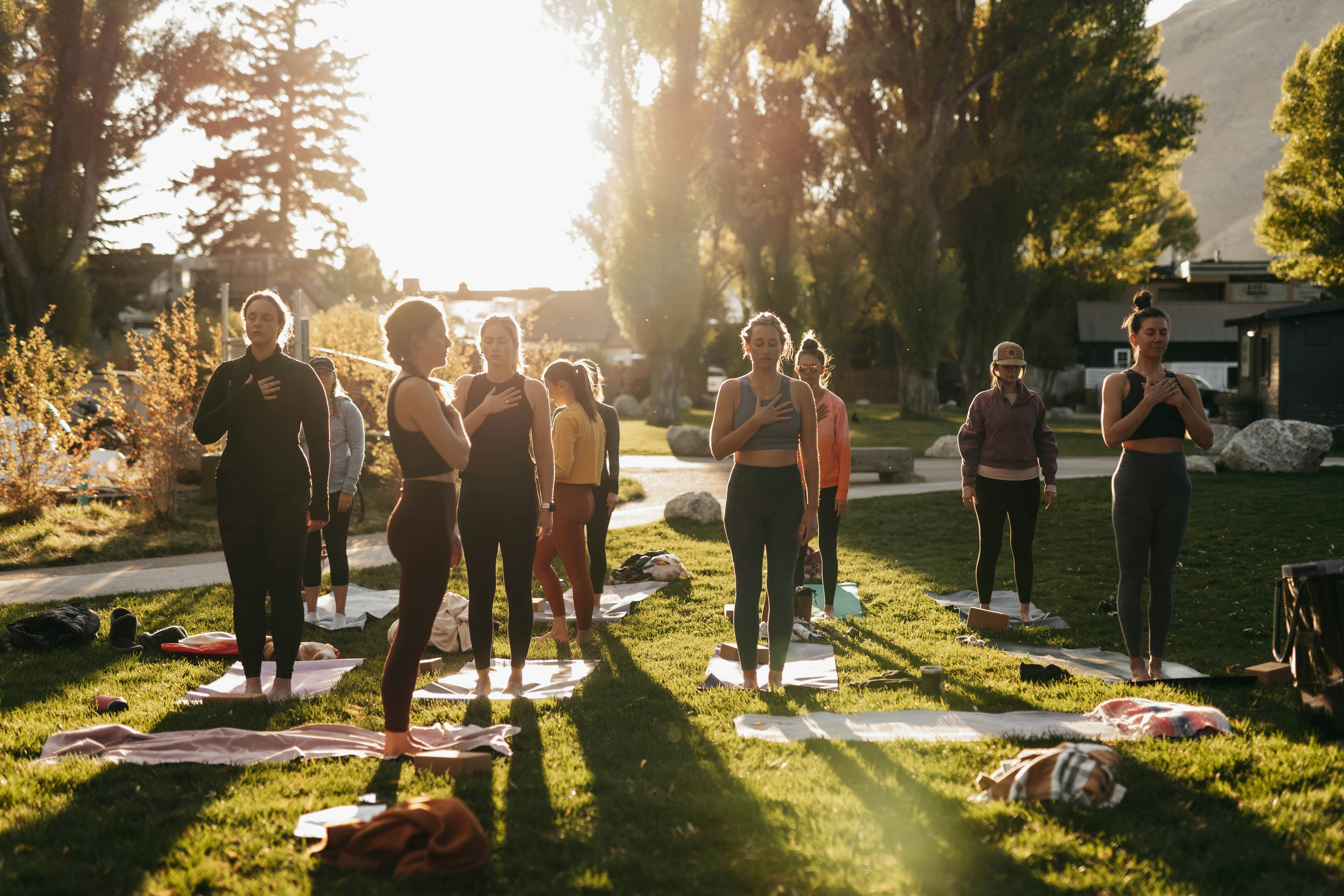 Grupo practicando yoga al aire libre al atardecer